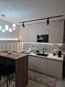 a kitchen with white cabinets and a sink and a table at Centar Spa Teslic in Teslić