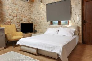 a bedroom with a bed and a chair and a television at Living in in Afitos