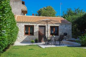 a small stone house with a table and an umbrella at Living in in Afitos