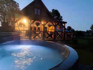 a house with a large swimming pool in front of a house at Jesionowy Zakątek domki z balią blisko jeziora in Piasutno