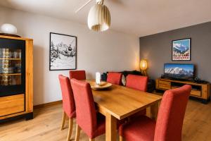 a dining room with a wooden table and red chairs at Apartment Picasso in Chamonix