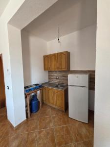 a kitchen with wooden cabinets and a white refrigerator at Vila Flamuri in Golem