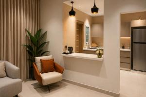 a living room with a couch and a chair and a kitchen at Abu Rakan Apartment in Muscat