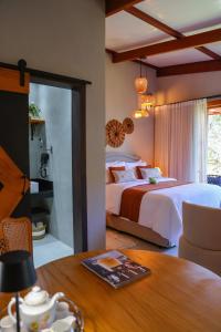 a bedroom with a large bed and a table at Fruto Vermelho Pousada in Pedra Menina