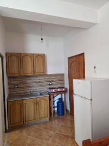 a kitchen with wooden cabinets and a white refrigerator at Vila Flamuri in Golem +21 photos