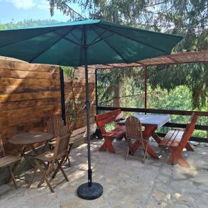 a table and chairs under a green umbrella at Vikendica Breza 2 in Zaovine