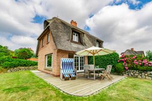 a house with a deck with a table and an umbrella at Haus Düne in List