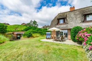 a large stone house with a picnic table and umbrella at Haus Düne in List