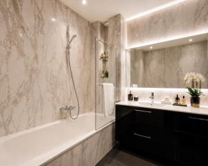 a bathroom with a tub and a sink and a shower at LUXUEUX APPARTEMENT AU COEUR DE GENEVE ,a deux pas du LAC in Geneva