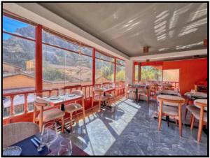 a restaurant with tables and chairs and large windows at Sol Ollantay Boutique Hotel in Ollantaytambo