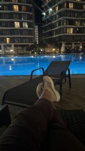 a person sitting on a bed in front of a pool at night at Квартира у моря с бассейном in Batumi +52 photos