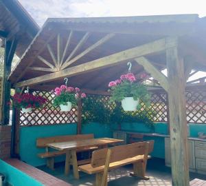 a wooden table and bench under a pergola with flowers at Kapitańska Przystań in Chłopy