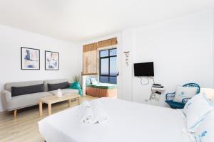 a white bedroom with a bed and a couch at Don Rafael # Ocean views # Natural pools in Bajamar