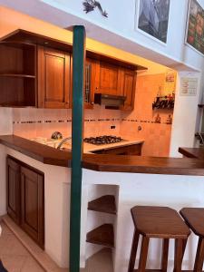 a kitchen with wooden cabinets and a counter with stools at Appartamento elba da Susanna in Portoferraio