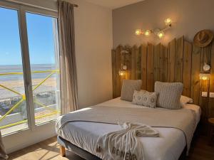 a bedroom with a bed and a large window at Acadie Saint Victor - Hôtel restaurant -Face mer- Châtelaillon plage in Châtelaillon-Plage