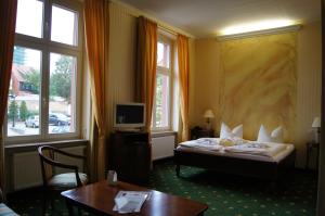 a hotel room with a bed and a desk and window at Müritz Hotel Harmonie in Waren