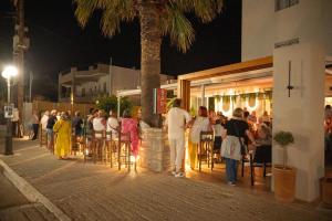 a group of people standing outside a restaurant at night at Matala Bay Hotel in Matala +62 photos