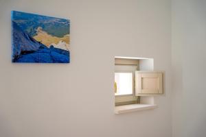 a painting hangs on a wall next to a window at 99 Rooms in LʼAquila