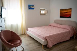a bedroom with a pink bed and a chair at 99 Rooms in LʼAquila