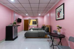 a bedroom with pink walls and a bed and a table at PoonsukPlace Sampran in Ban Bang Yai Chuai