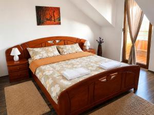 a bedroom with a large wooden bed with two pillows at Vila Ţara Haţegului in Haţeg +36 photos
