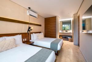 a hotel room with two beds and a bathroom at Collection O Faisano Boutique Luxury Hotel, Tulum Beach in Tulum
