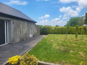 a garden next to a stone building with a yard at Farm Cottage in Athy +7 photos