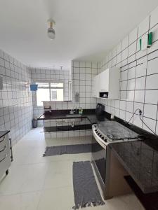 a kitchen with black and white tiled walls at Praia Morro Katia apartamentos - Edificio Porto Belo in Guarapari +15 photos