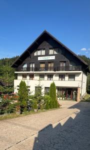 a large white building with a black roof at Hotel boutique Garden Resort by Brancoveanu in Moieciu de Jos