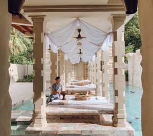 a man sitting in the middle of a pavilion with a table at Devasom Khao Lak Beach Resort & Villas in Khao Lak