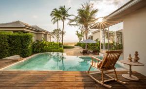 a villa with a swimming pool and a chair at Devasom Khao Lak Beach Resort & Villas in Khao Lak