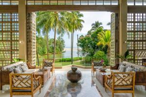 a living room with a view of the ocean at Devasom Khao Lak Beach Resort & Villas in Khao Lak