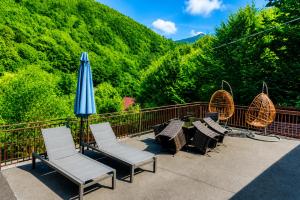 a group of chairs and an umbrella on a balcony at Iezer Mountain Escape in Lunca Ampoiţei