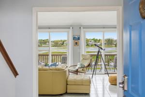a living room with a door open to a porch with a chair at Waterfront Escape with Stunning Views on Bass River in West Dennis