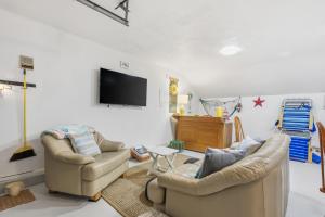 a living room with two chairs and a flat screen tv at Waterfront Escape with Stunning Views on Bass River in West Dennis