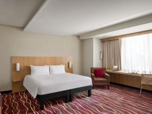 a bedroom with a bed and a chair and a window at ibis Kuwait Salmiya in Kuwait +108 photos