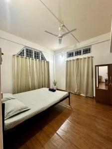 a bedroom with a bed and two windows at The Gulmohar Grove in Pāsighāt