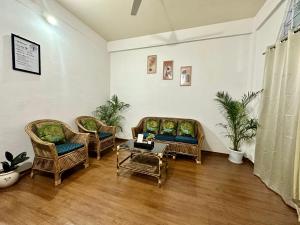a living room with wicker chairs and a table at The Gulmohar Grove in Pāsighāt
