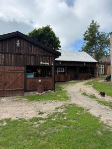 a barn with a dog standing in front of it at Loukis dvars in Luokė