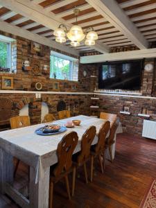a dining room with a table and chairs and a tv at Loukis dvars in Luokė