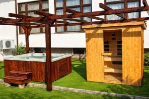a wooden house with a hot tub and a wooden pergola at Хотел Кючуковата Къща in Banite