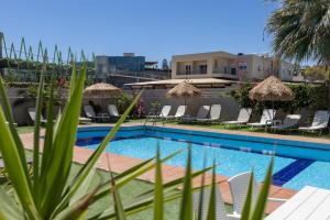 a swimming pool with chairs and umbrellas at Nikolas Apartments in Amoudara Herakliou