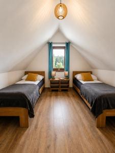 a attic bedroom with two beds and a window at Apartamenty Wisła Krzywa 8, wanna z hydromasażem, basen zewnętrzny in Wisła +96 photos
