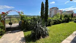 a garden with a gate and a plant in the grass at AMADEUS I Studio 25 Sunny Beach in Sunny Beach