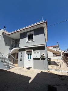 a gray house with a white door and stairs at Katies cozy corner in Chios