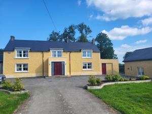 a yellow house with a red door on a driveway at Farm Cottage in Athy