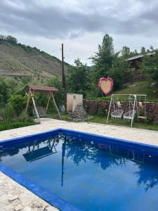 a blue swimming pool in a yard with a swing at Green Garden in Alayaz +17 photos