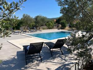 a swimming pool with chairs and a table and a swimming pool at Pax et Bonum in Lozovac