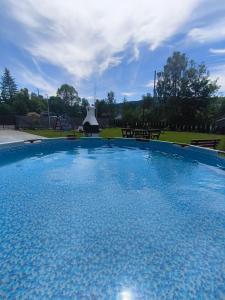 a large blue swimming pool with a picnic table in a park at Apartamenty Wisła Krzywa 8, wanna z hydromasażem, basen zewnętrzny in Wisła