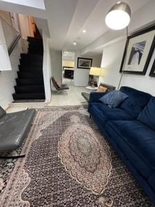 a living room with a blue couch and a staircase at COMFY Basement Home 2 Bdrm1Den 3Queen Beds in Washington, D.C.